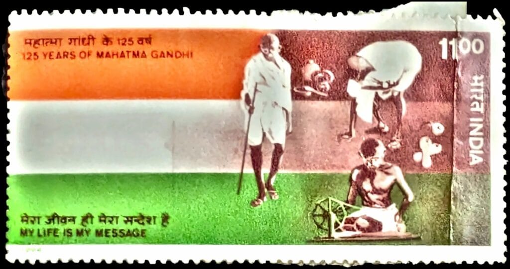 1994 Gandhi stamp India, ₹11 tricolour commemorative showing Gandhi walking, bowing, and spinning at the charkha, with the inscription My Life Is My Message