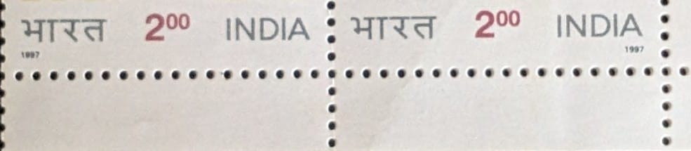 Perforation detail across the join of the 1997 Philatelic Society stamp se-tenant pair, showing the tooth spacing and the unmounted mint paper condition