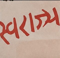 Macro close-up of the oversized "Swaraj" text on the Tilak stamp, red ink, hand-lettered style