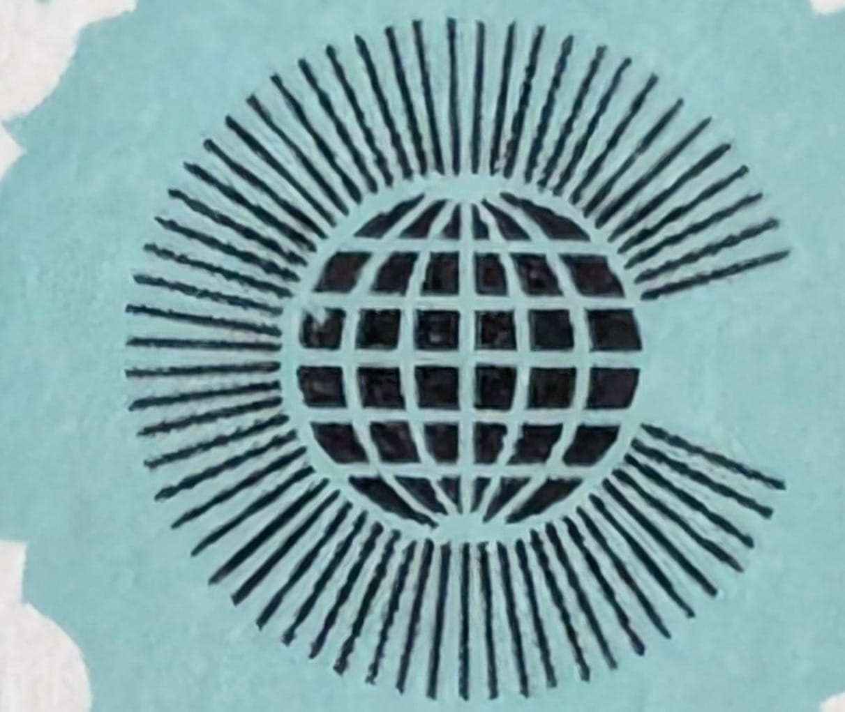 Macro of the Commonwealth emblem on the 1983 India stamp — a gridded globe encircled by radiating spears that open into a C on the right side