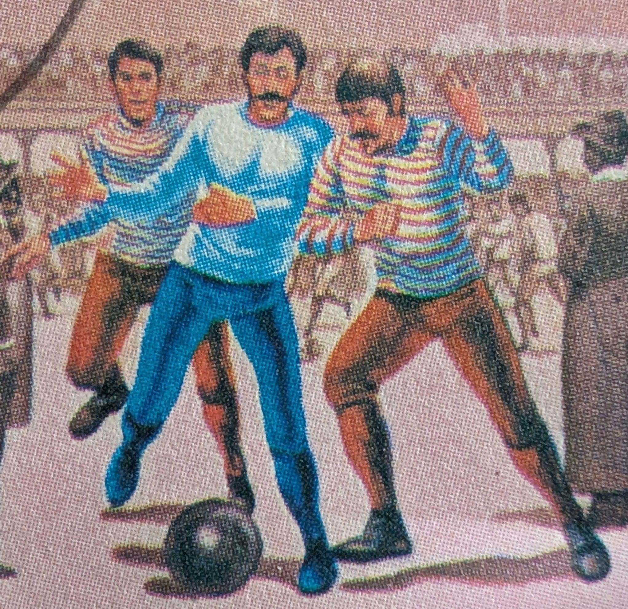 Macro of three footballers in collared striped jerseys, long trousers and laced boots contesting a dark leather ball on the 1985 Nicaragua stamp