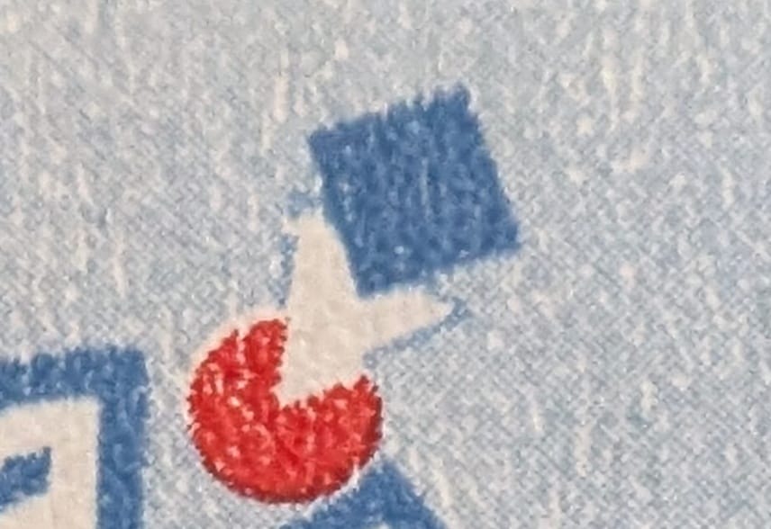 Macro of the small blue square and red disc above the emblem on the 1994 India Human Resource Development stamp, the single spot of red on the whole design