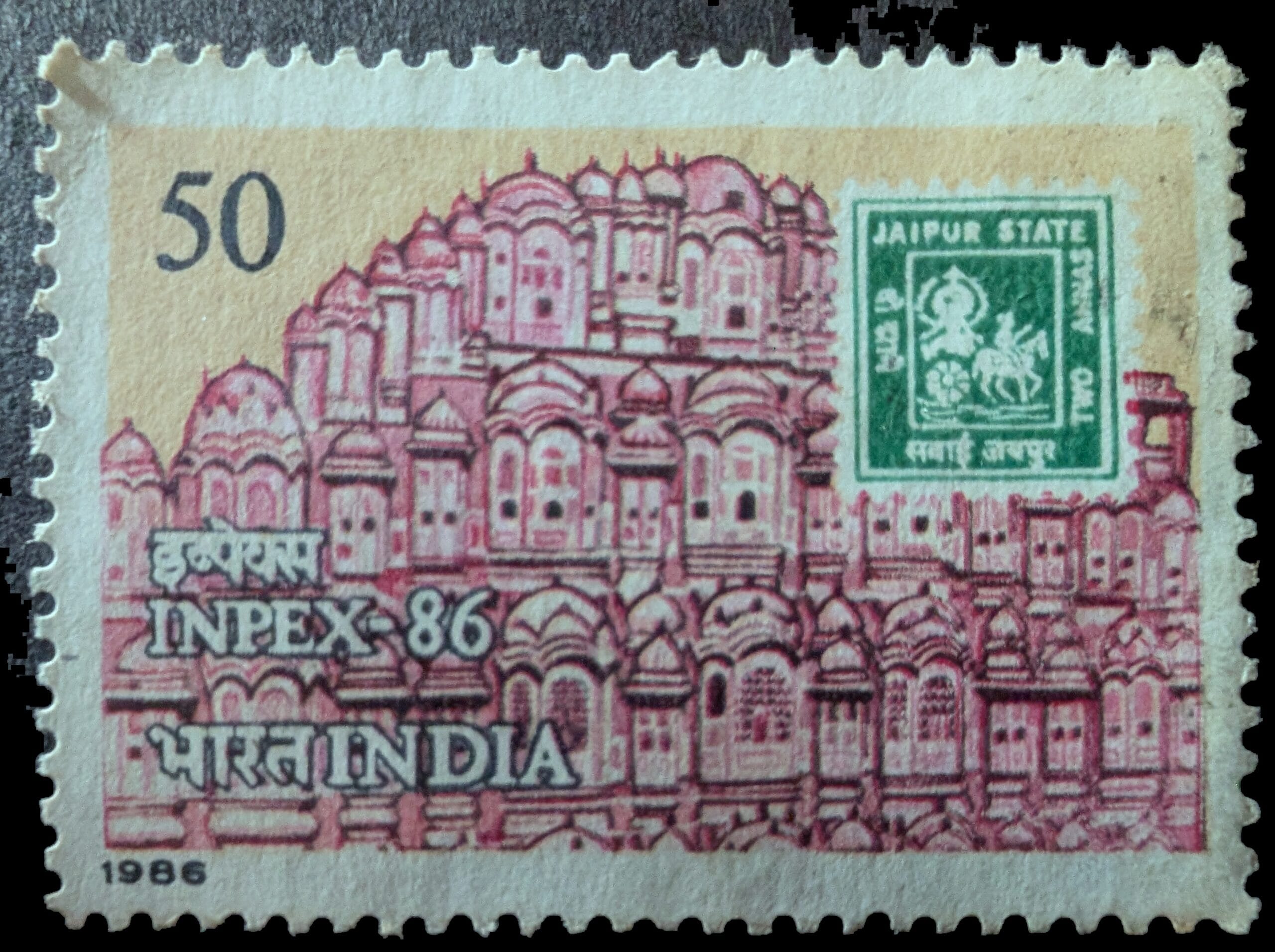 The complete 1986 India INPEX-86 stamp, 50 paise, the Hawa Mahal facade in red behind the INPEX-86 lettering with the green Jaipur State stamp inset upper right