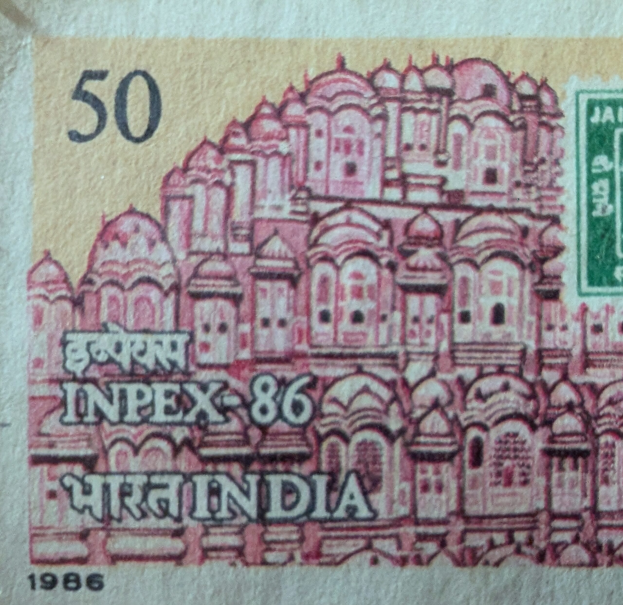Macro of the red Hawa Mahal facade engraved across the 1986 India INPEX-86 stamp, its tiered honeycomb of windows filling the frame
