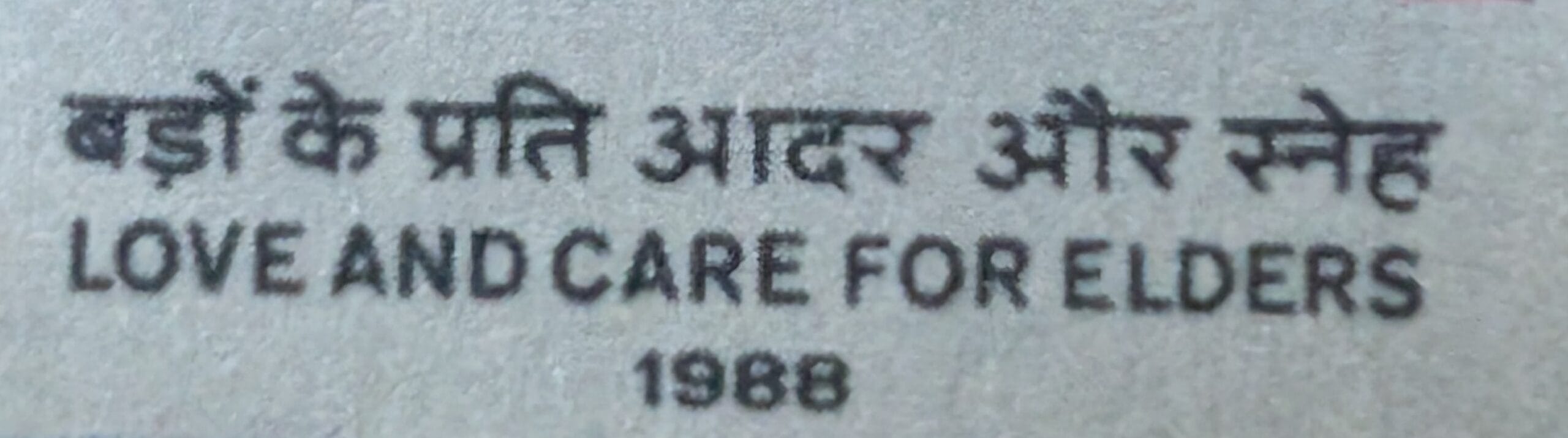 Macro of the bilingual caption band reading बड़ों के प्रति आदर और स्नेह above LOVE AND CARE FOR ELDERS on the 1988 India stamp
