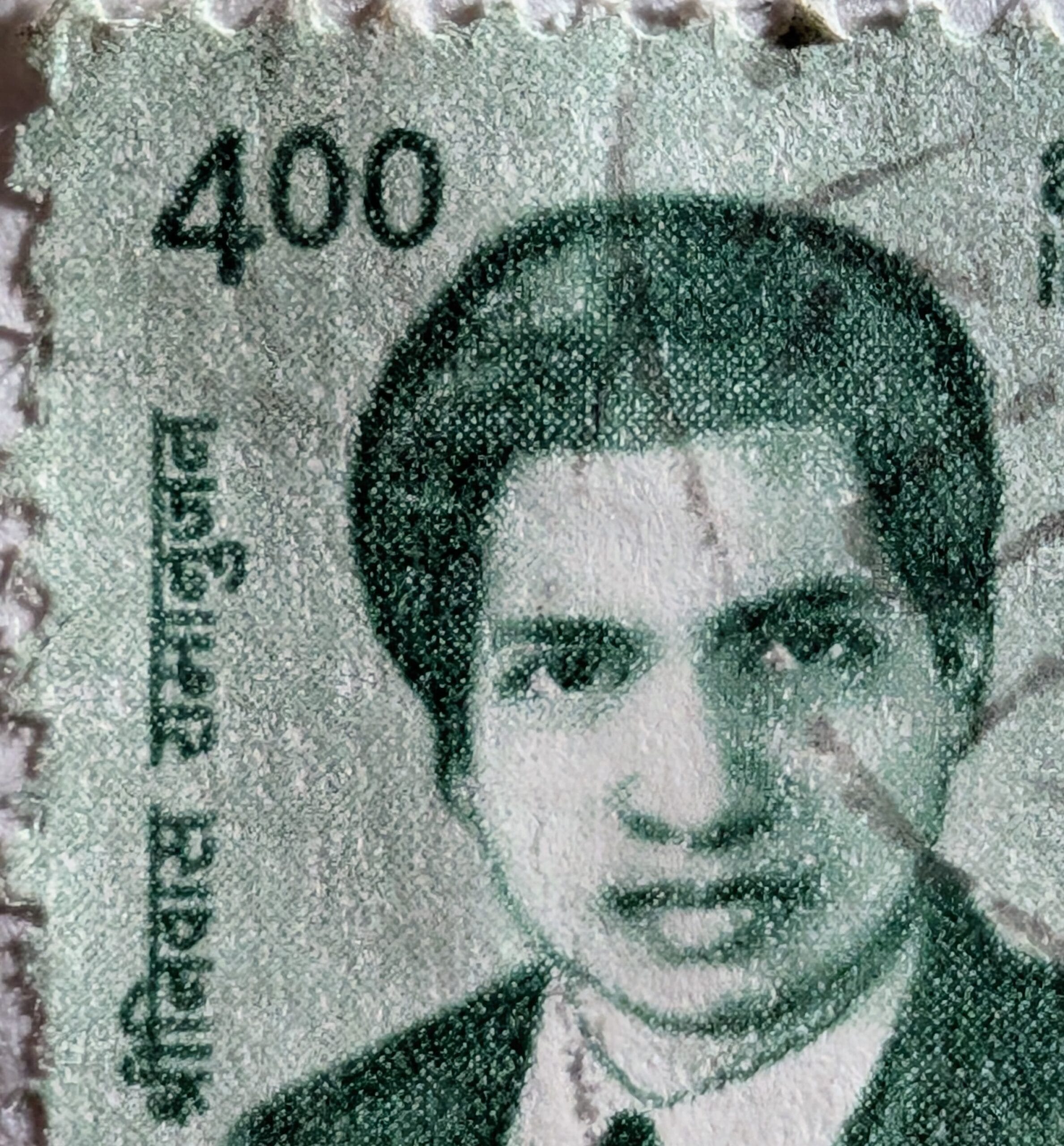 Macro of the Srinivasa Ramanujan stamp denomination corner showing the four-rupee value and the portrait rendered as a green halftone dot screen