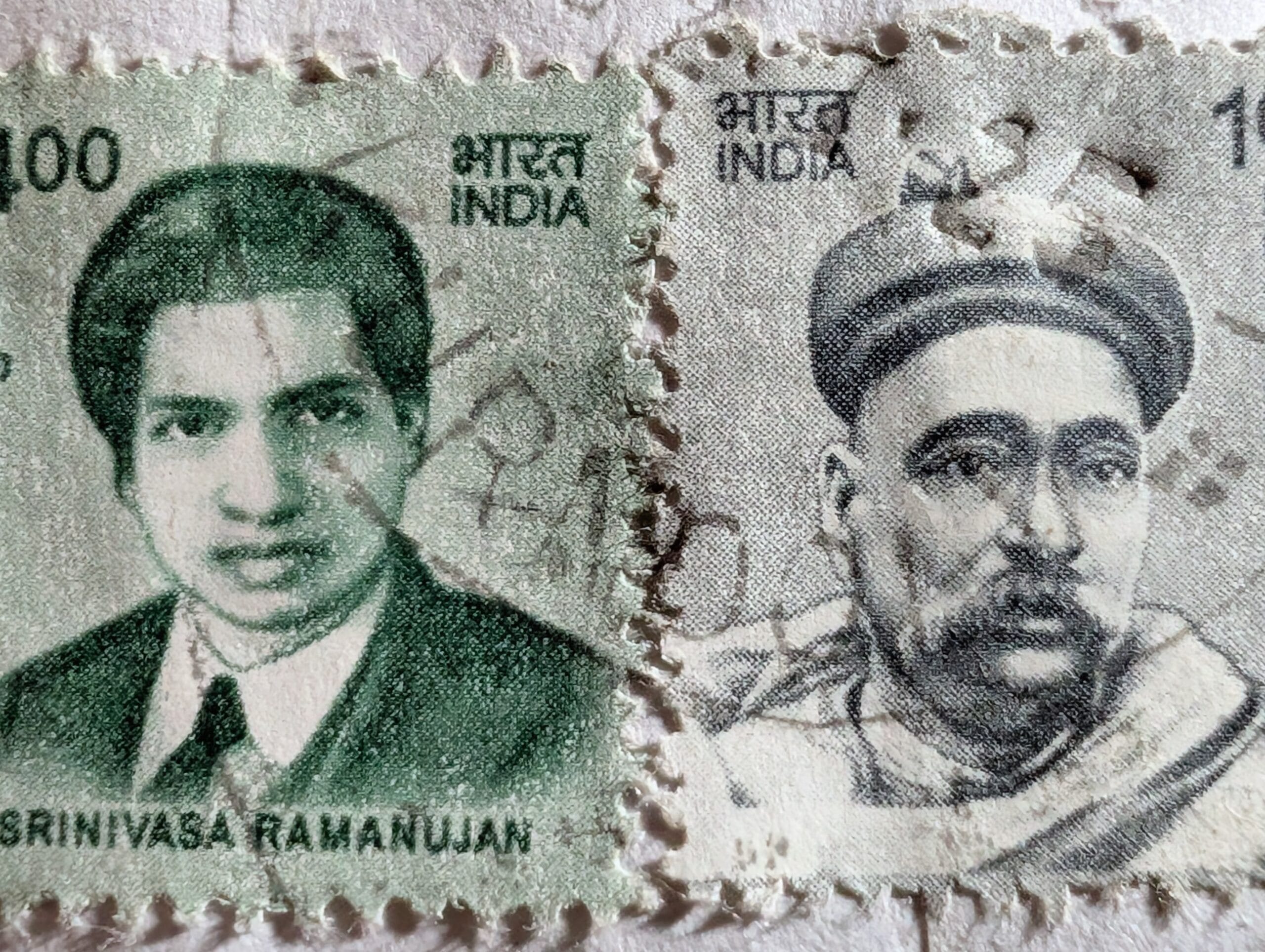 The join where the green Srinivasa Ramanujan stamp meets the grey Bal Gangadhar Tilak definitive, both built from the same template