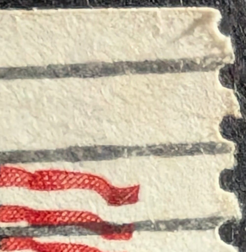 Macro of the top-right corner of the 1978 Fort McHenry Flag coil stamp showing perforations along the vertical edge and a straight, uncut top edge